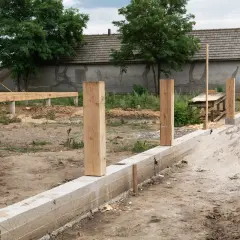Drewniane słupy na fundamencie, plac budowy z fundamentem i konstrukcją drewnianą.